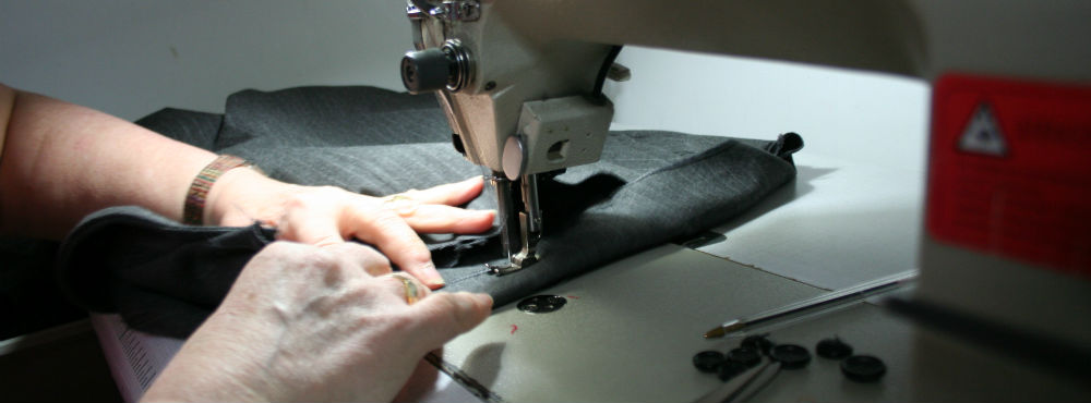 Costurera y máquina de coser Unas manos cosiendo a máquina un bajo de un pantalón